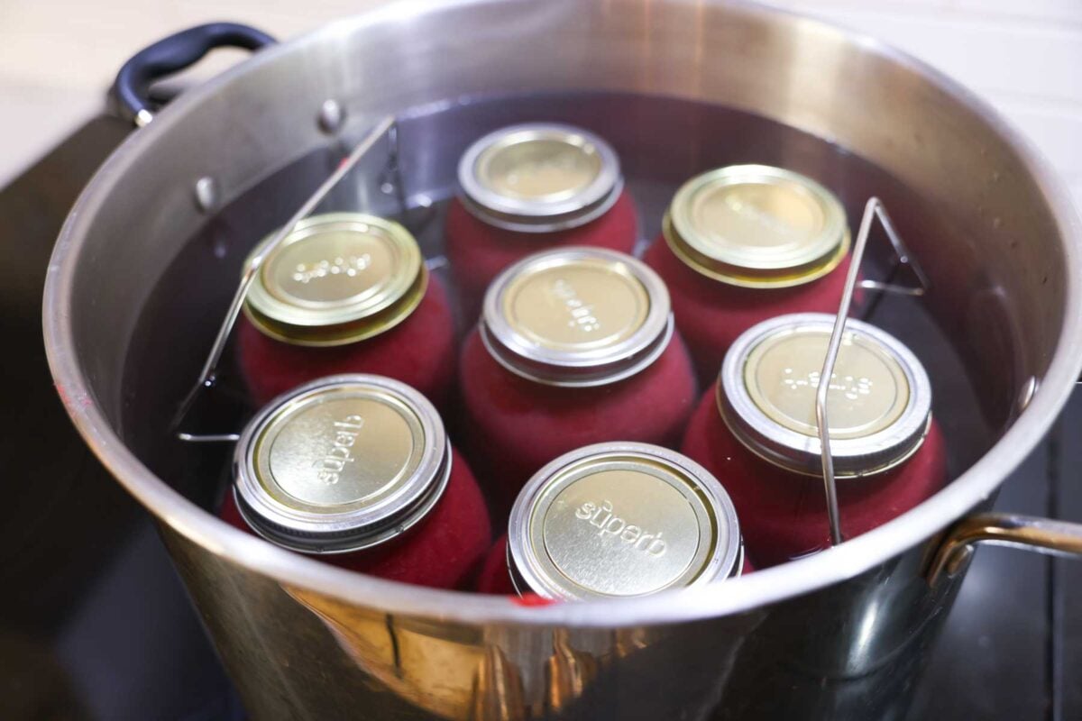 Jars filled with Cranberry applesauce in a water bath canner are cooking.