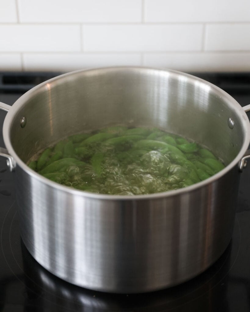 Snap peas inside a pot filled with boiling water.