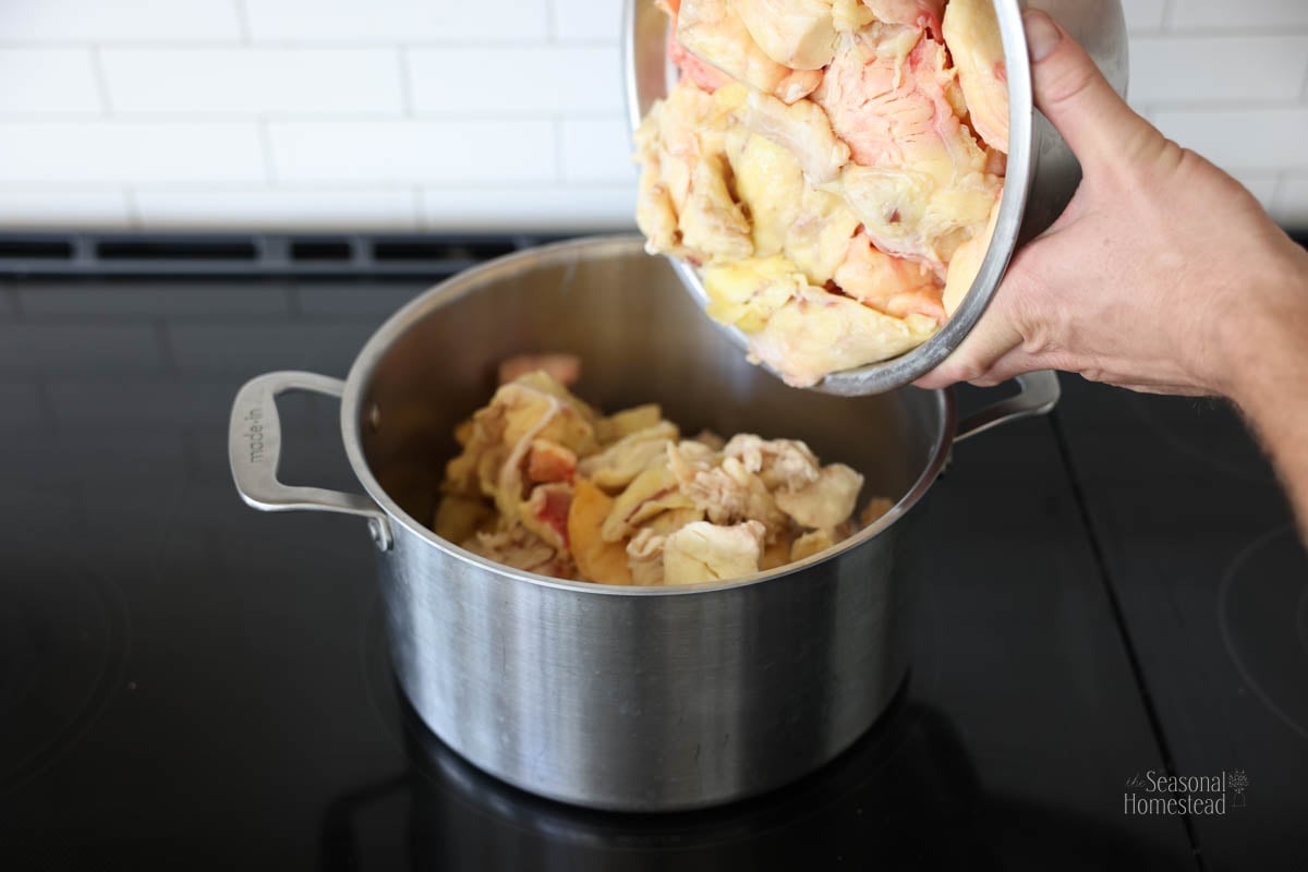 pouring the trimmed beef fat into a large pot in preparation for rendering.