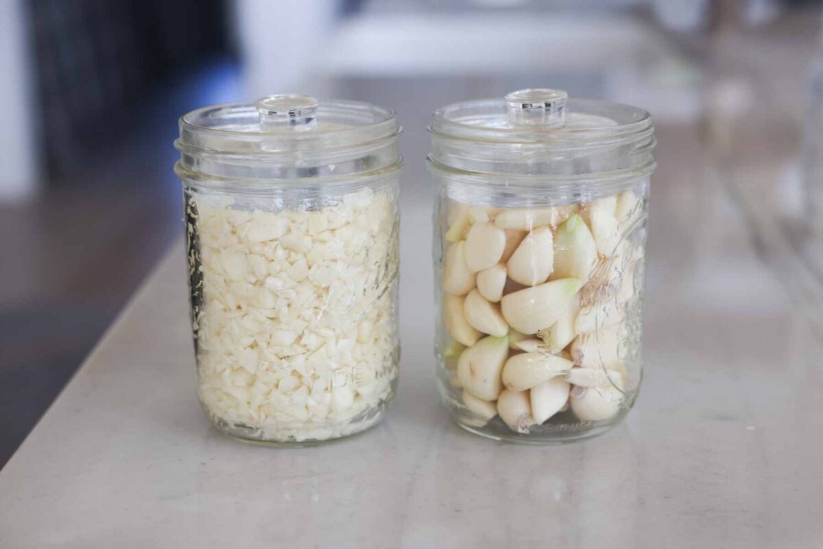 Jars of garlic with a weight on the top.