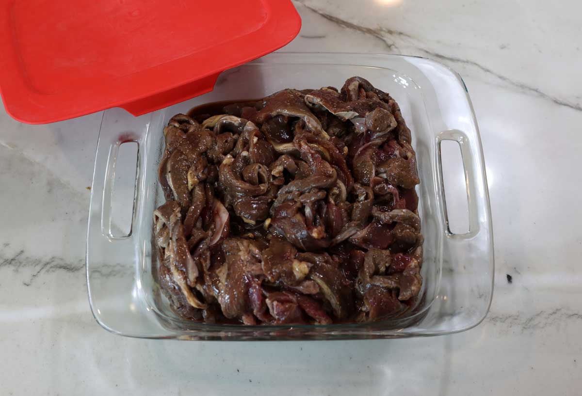 beef slices in marinade, in a glass dish