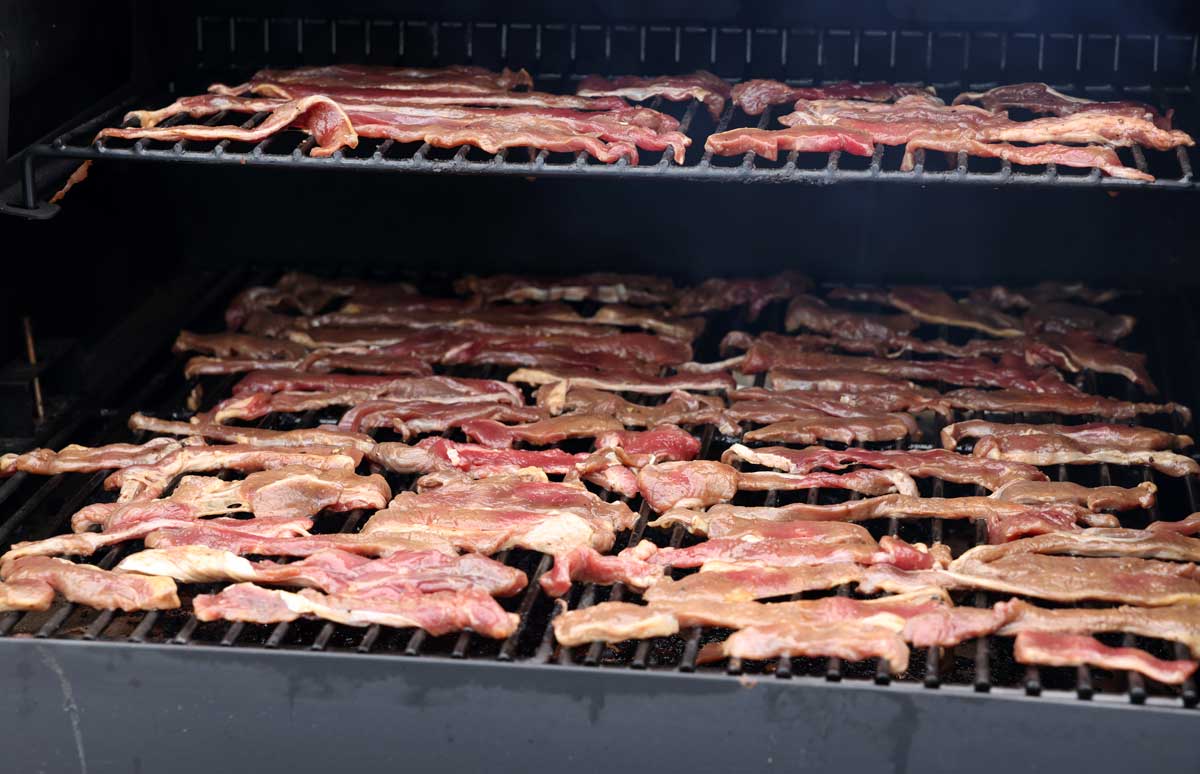raw marinated meat just placed on the smoker for turning into jerky