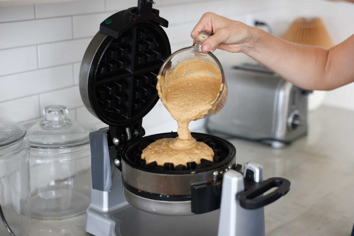 whole wheat pumpkin waffle batter being poured into a waffle iron.