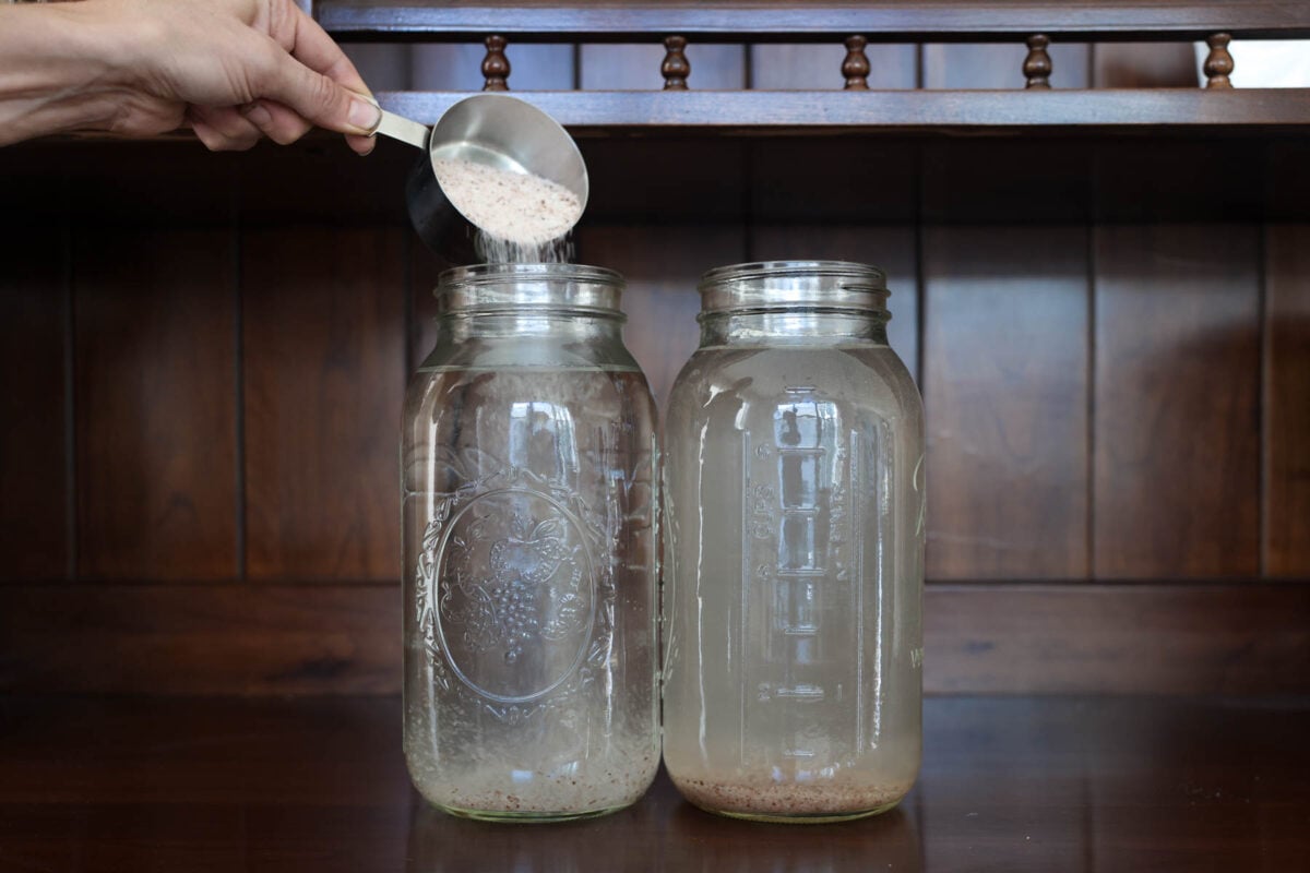 Pouring salt into water to make a brine for fermenting pickles.