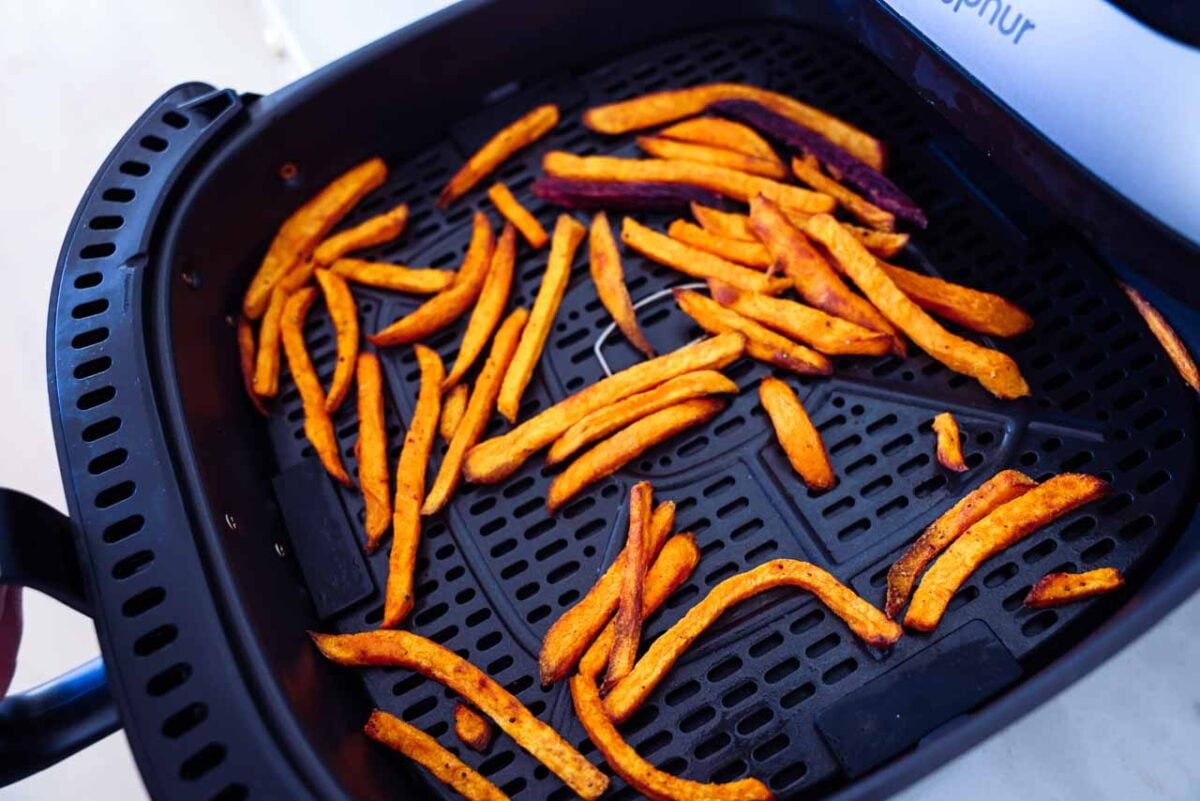 Cooked homemade sweet potato fries are shown in an air fryer.