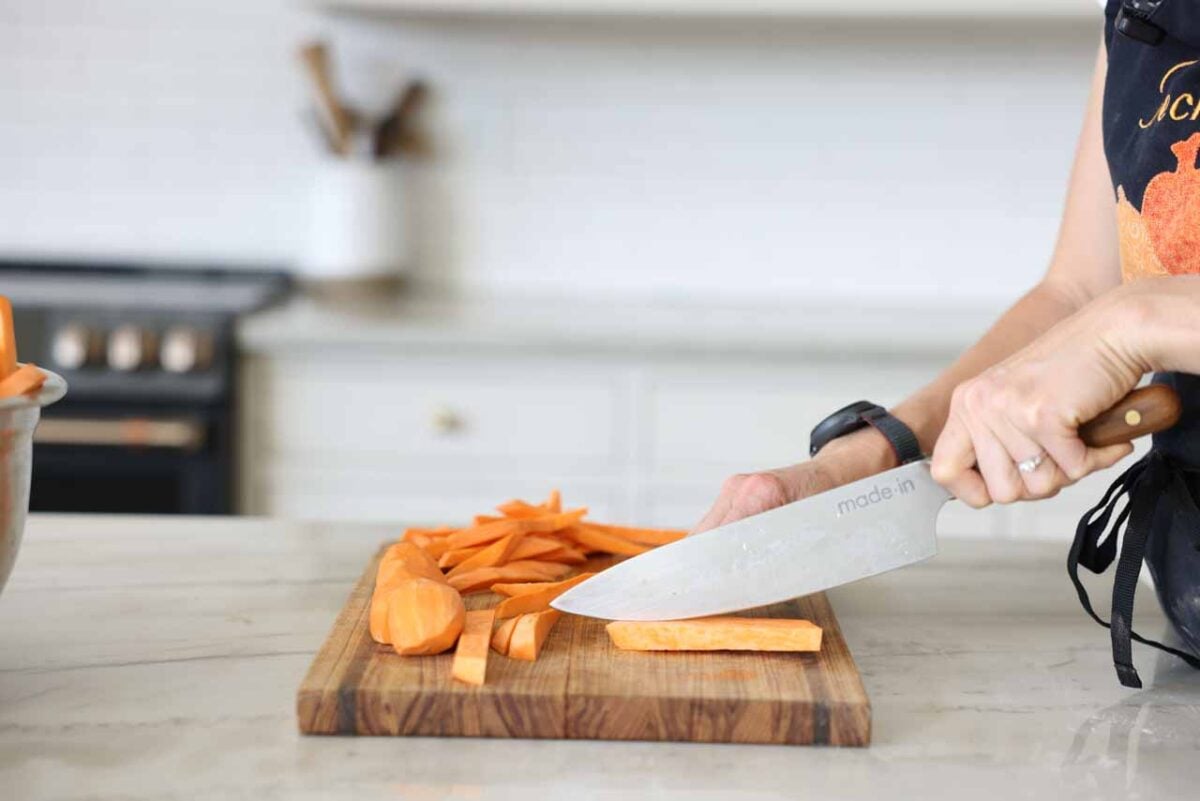 Sweet potatoes are being cut on a cutting board.