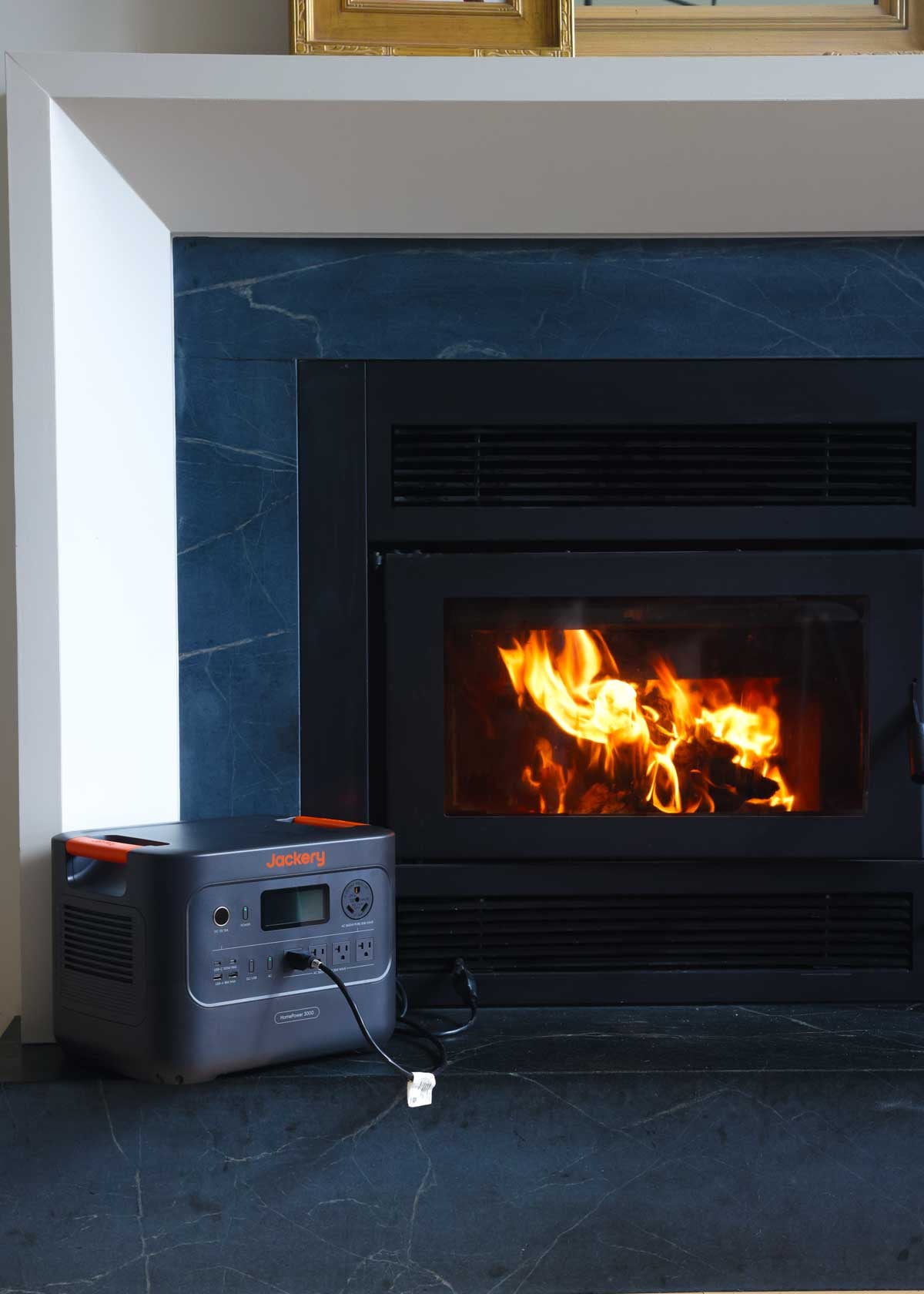 A battery powered backup generator is next to a fireplace powering the fan.