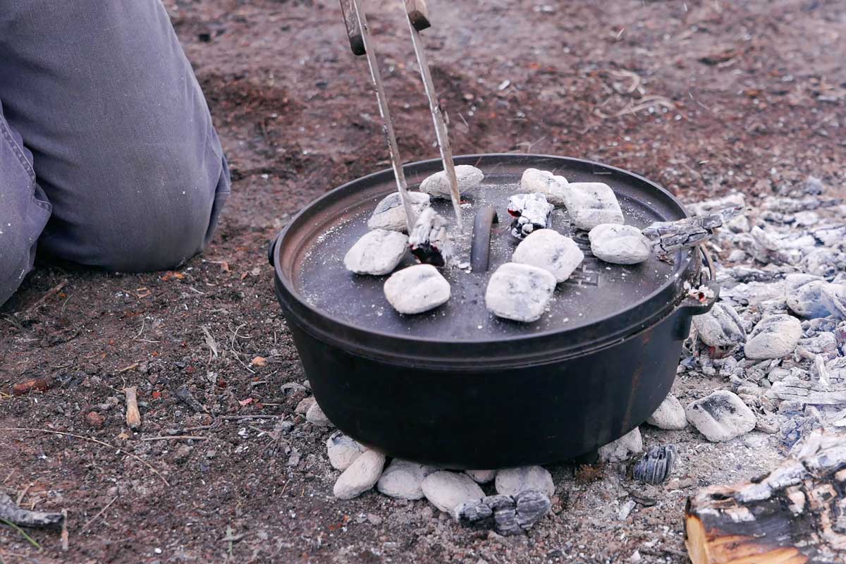 Cooking with coals and a dutch oven over an open fire.