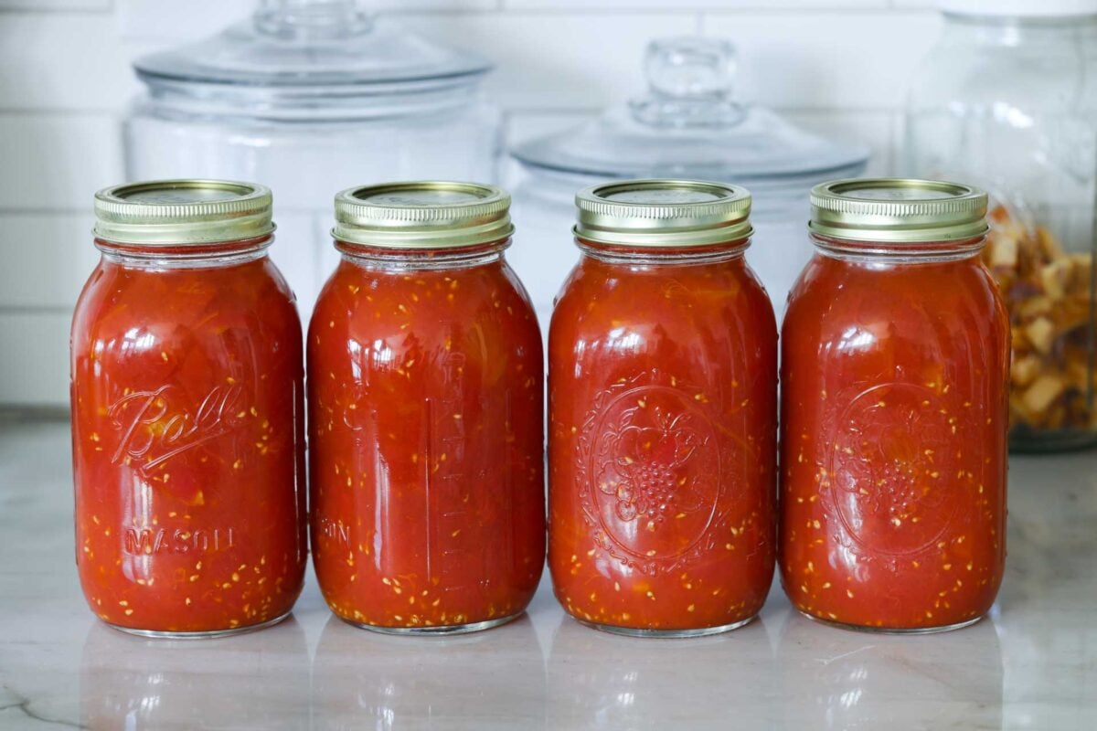 Finished jars of diced tomatoes rest on the counter.