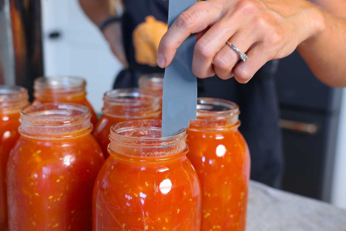 Measuring a half inch of headspace for water bath canning diced tomatoes.