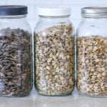 different types of sunflower seeds in mason jars on a kitchen counter for display