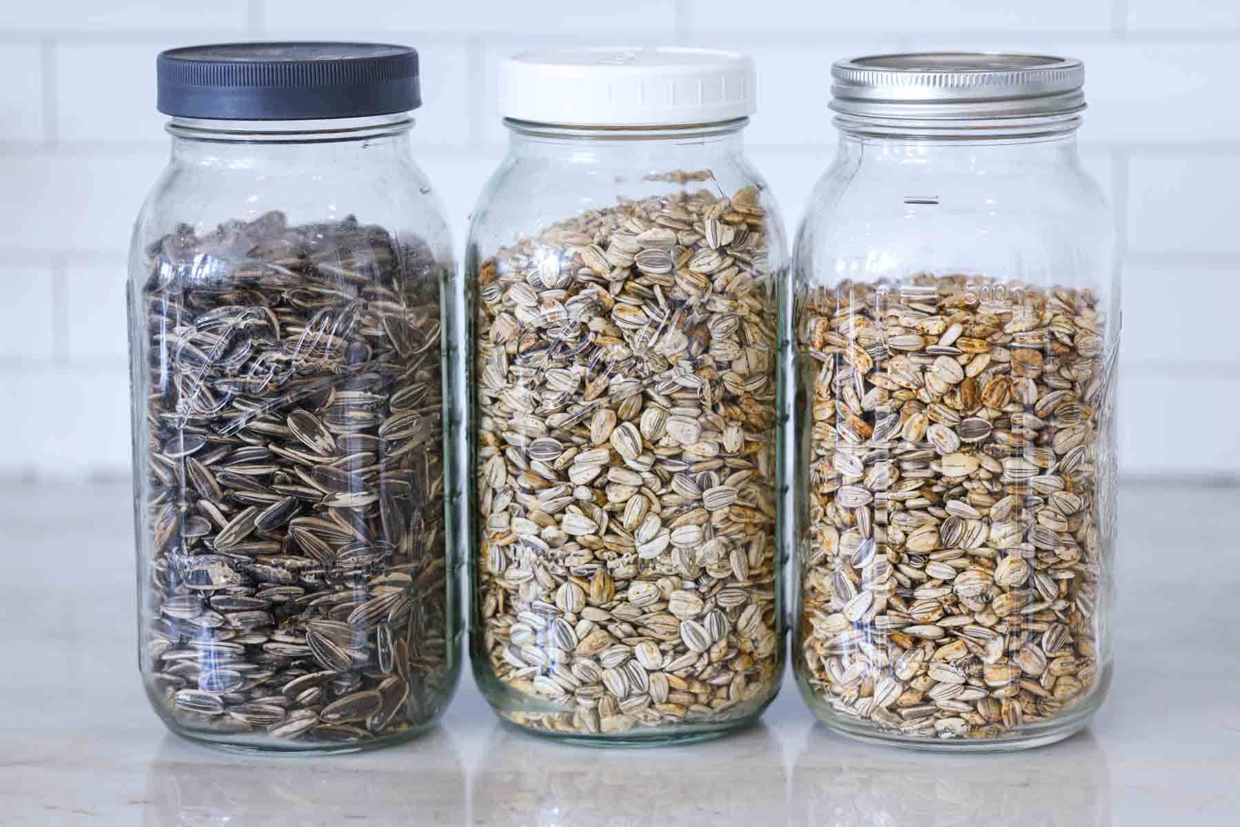 different types of sunflower seeds in mason jars on a kitchen counter for display