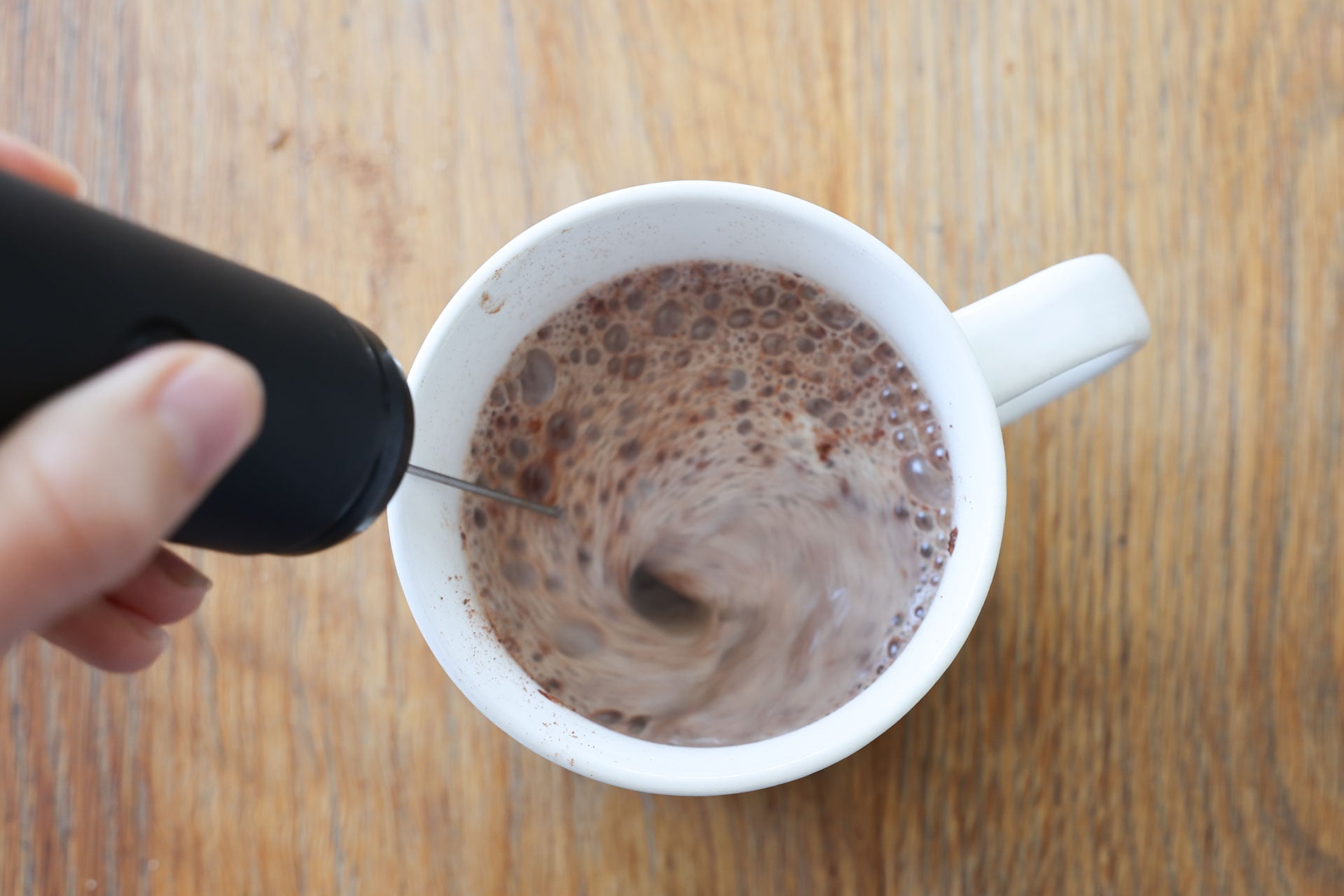 Using a frother to mix hot cocoa with milk